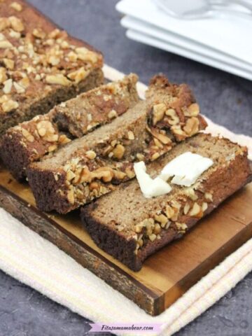 sugar-free banana bread cut in slices on a cutting board with one slice topped with dairy-free butter