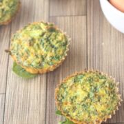Dairy-free egg muffins in a line seated on spinach with eggs and spinach in white bowls.