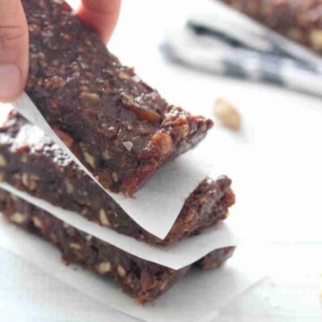 Fingers placing a mint chocolate protein bar onto a stack.