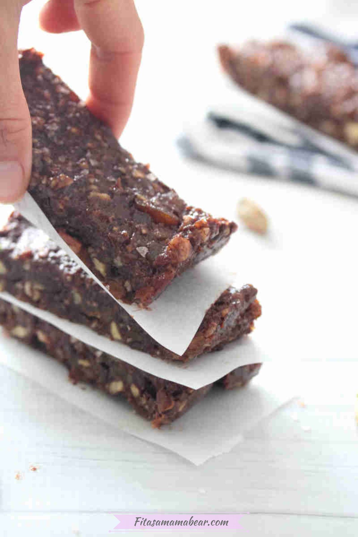 Fingers placing a mint chocolate protein bar onto a stack.