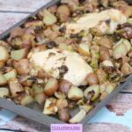 Sheet pan with chicken breasts, potatoes, and Brussels sprouts on it.