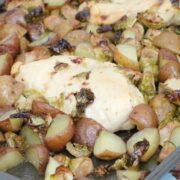 Sheet pan with chicken breasts, potatoes, and Brussels sprouts on it.