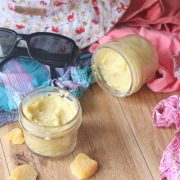 Homemade all natural sunscreen in jars next to beach clothes