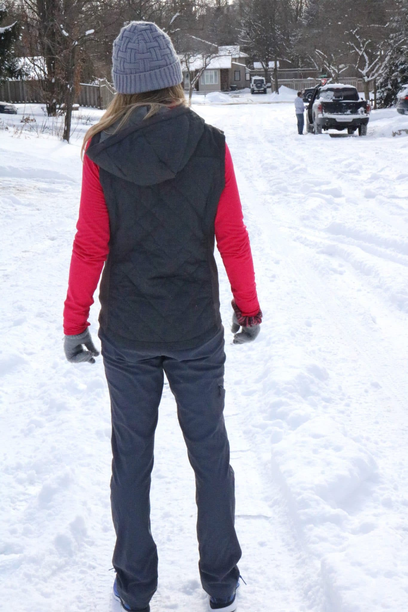 Woman ni a vest and black pants getting ready to run in the snow