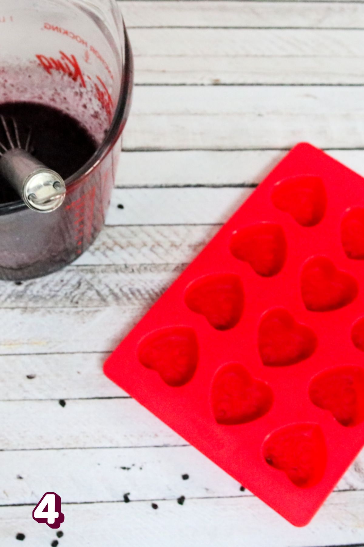 Elderberry gummy mixture in a measuring cup beside a red silicone mold.