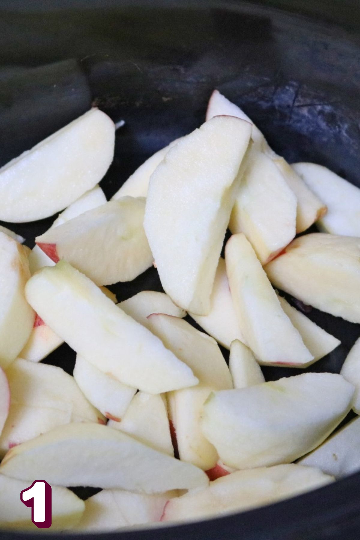 Sliced and peeled apples in a slow cooker.