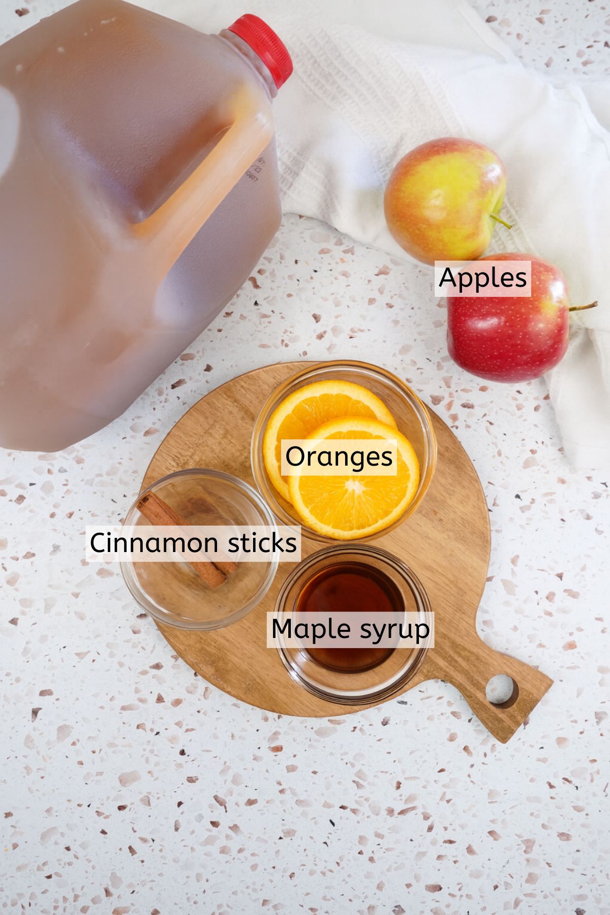 Ingredients to make apple cider on a cutting board with text labels over top.