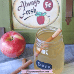 Pin image with text: how apple cider in a mason jar labeled cider with cinnamon and apple around it