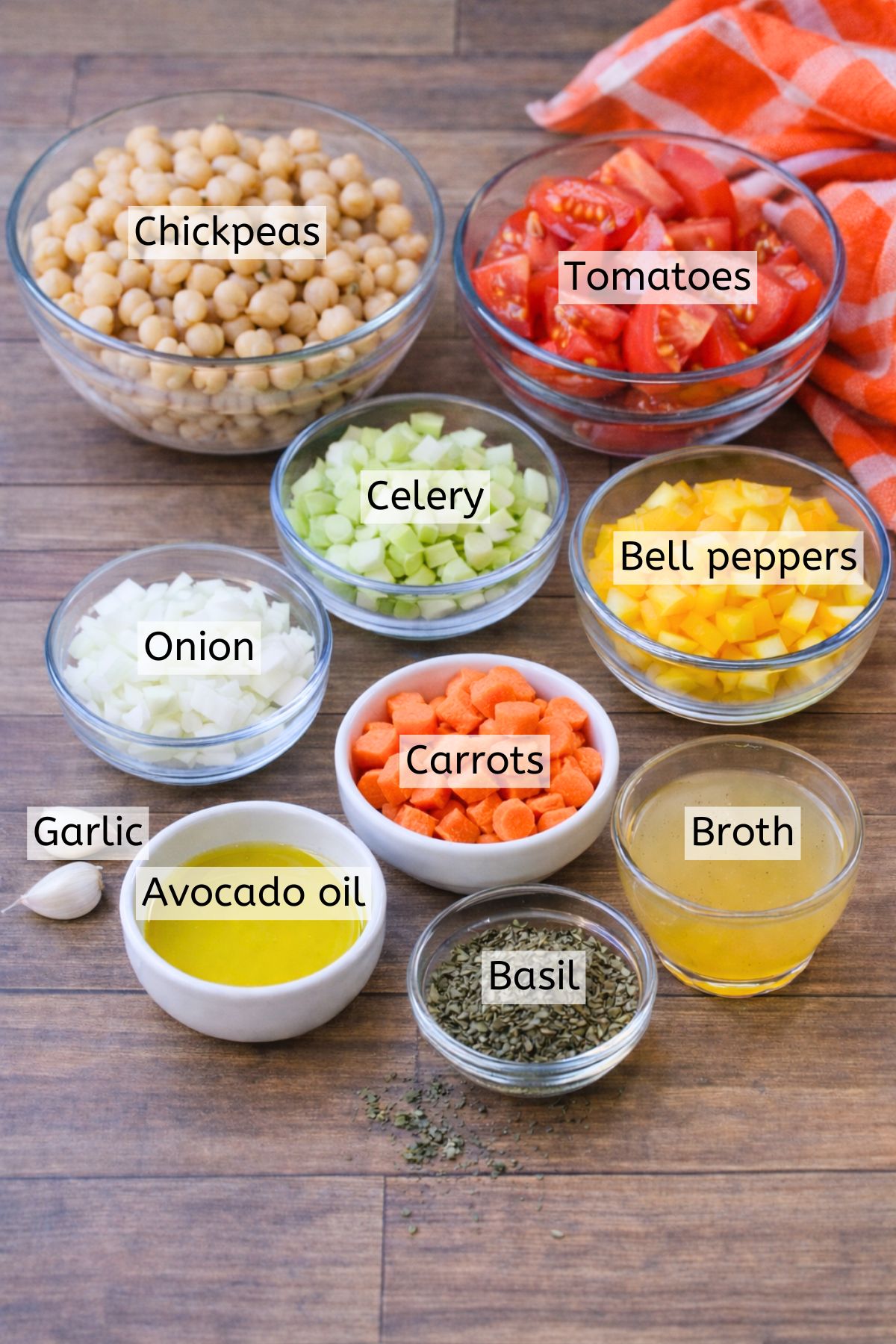 Multiple vegetables, chickpeas, tomatoes, and seasonings in glass jars with text labels over top.