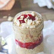 Close up of a mason jar with peanut butter and jelly overnight oats on a white cheese cloth.