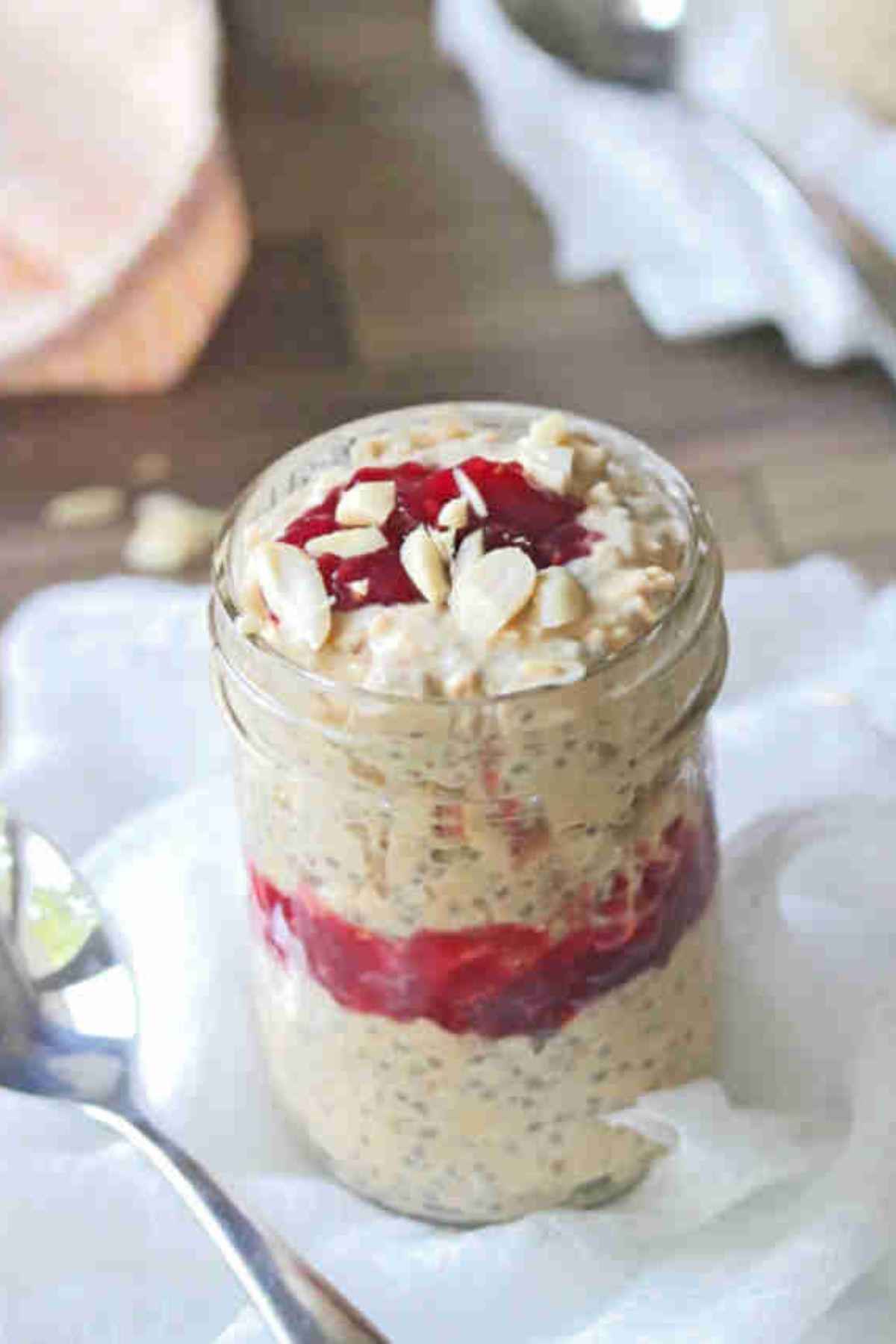 Close up of a mason jar with peanut butter and jelly overnight oats on a white cheese cloth.