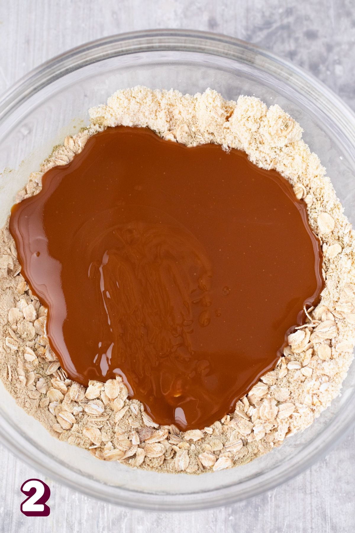 Glass bowl with chocolate and maple syrup poured in it over oats.