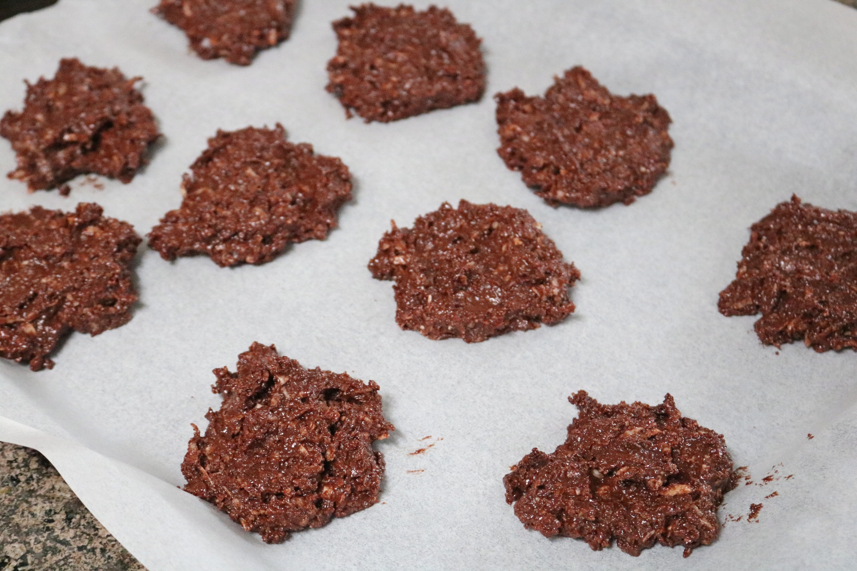 Chocolate cookies on a piece of white parchment paper before being cooked