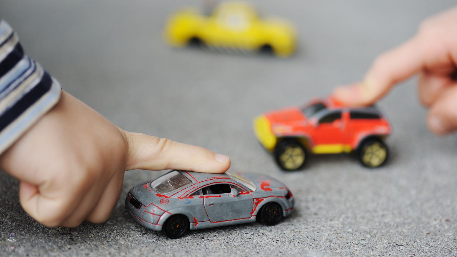 Toddler finger on toy race car with more race cars around it.