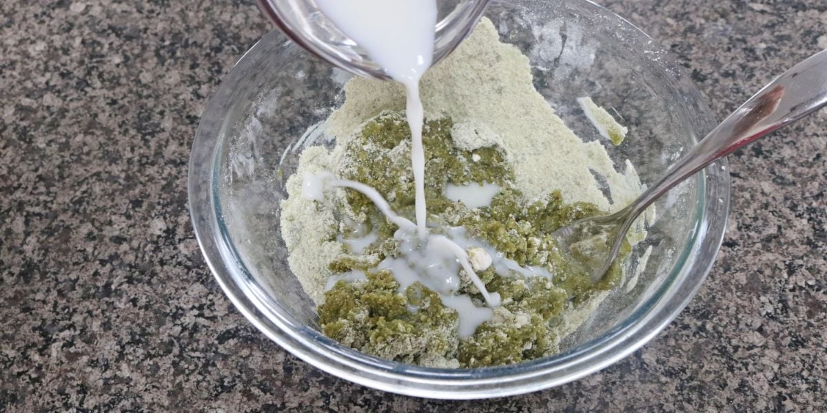 Milk being poured into matcha cookie dough ingredients.