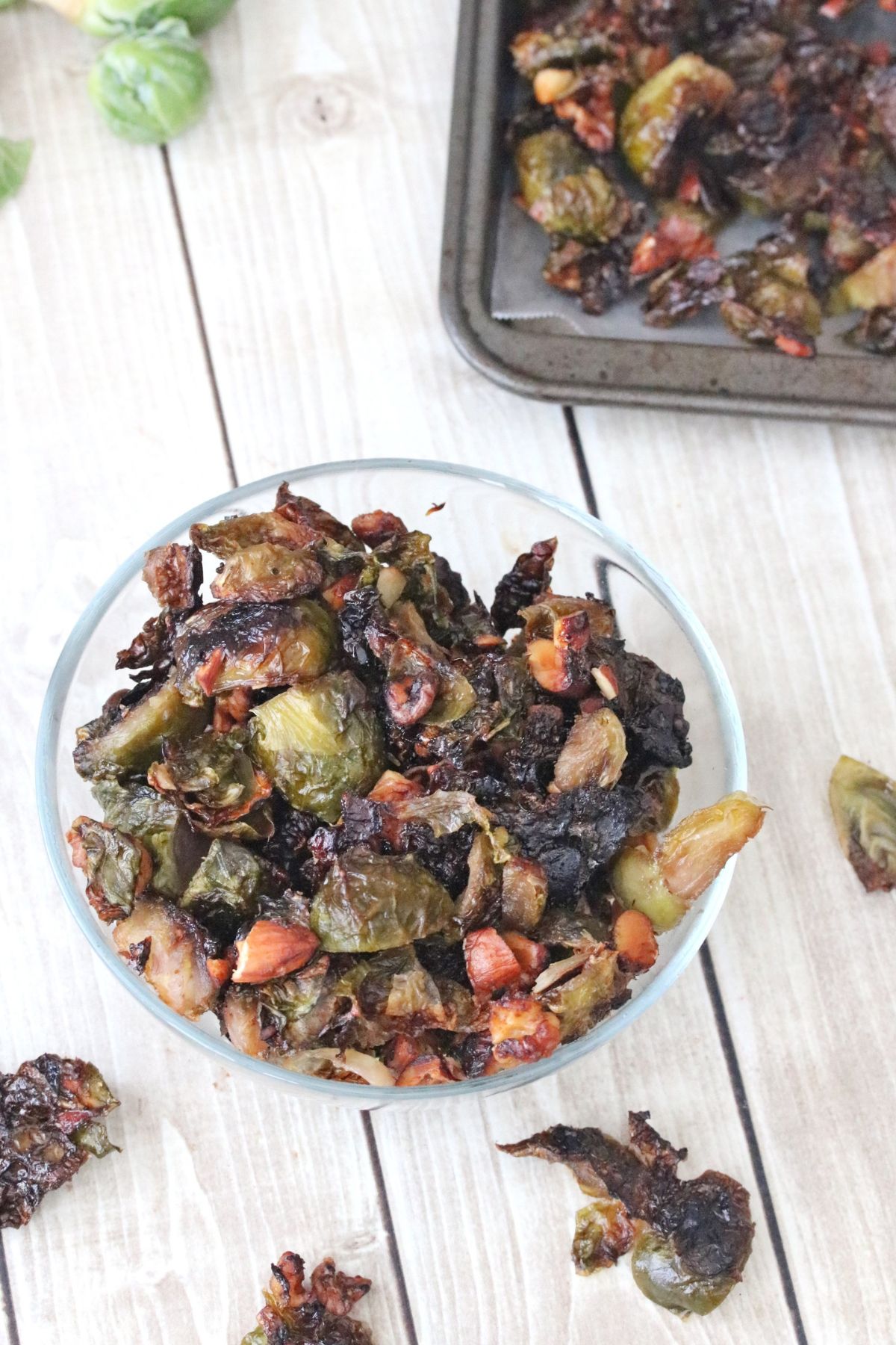Candied Brussels sprouts in a glass dish with more around it.