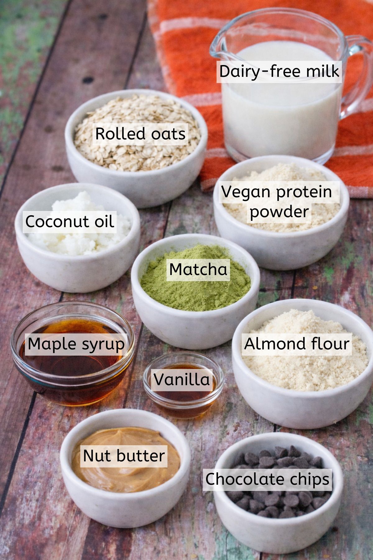 Multiple bowls with ingredients to make matcha protein bars and text labels over top.