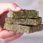 Three green protein bars held between fingers.