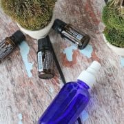 blue cobalt spray bottle on its side with essential oils and fake trees around it
