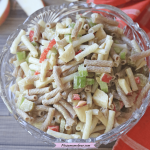 Pinterest image with text: large glass bowl with macaroni salad in it and orange linen on the side