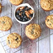 Paleo morning glory muffins on a cooling rack with a white bowl of blueberries and pecans in the middle