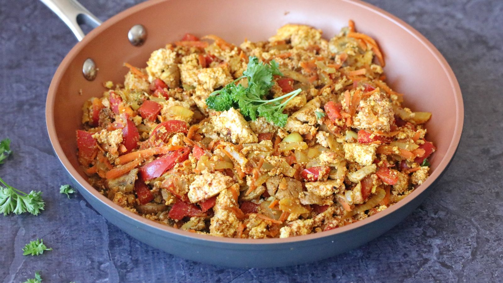 Healthy tofu scramble with veggies in a non-stick skillet.