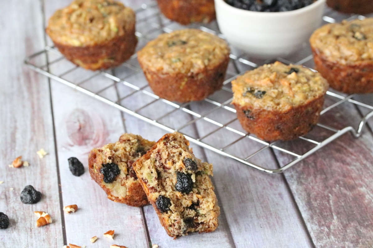 Paleo morning glory muffins on a cooling rack with a white bowl of blueberries and pecans in the middle