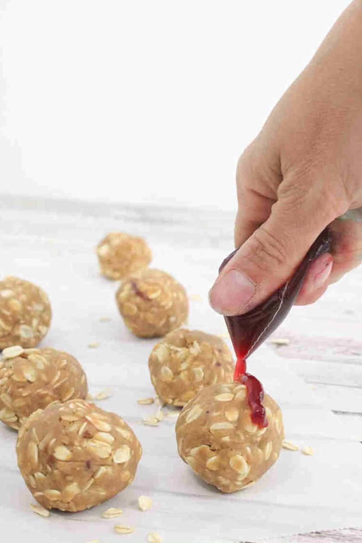 Jam being drizzled onto peanut butter oat protein balls.