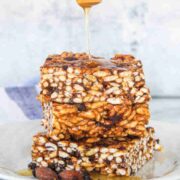 Honey drizzled onto rice crispy squares with chocolate chips in them.