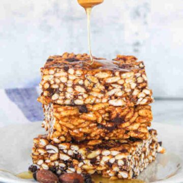 Honey drizzled onto rice crispy squares with chocolate chips in them.
