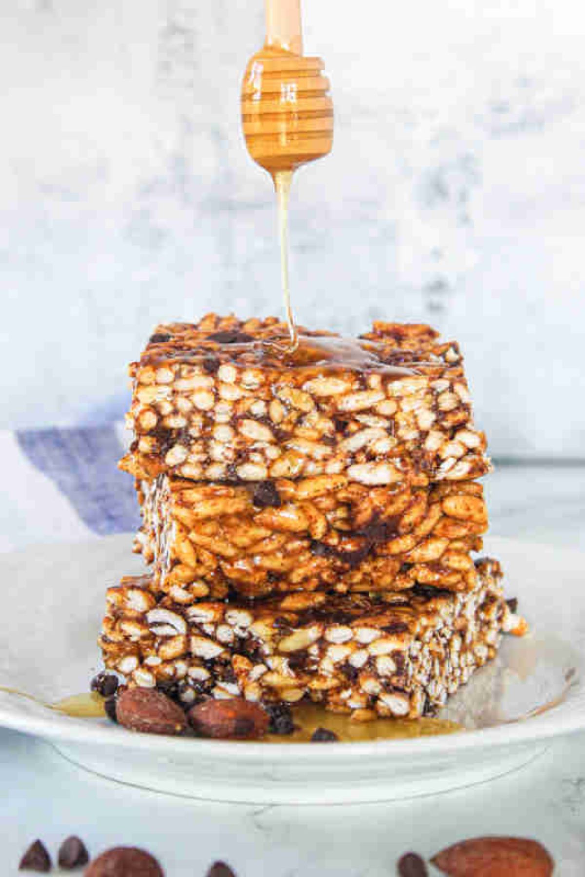 Honey drizzled onto rice crispy squares with chocolate chips in them.