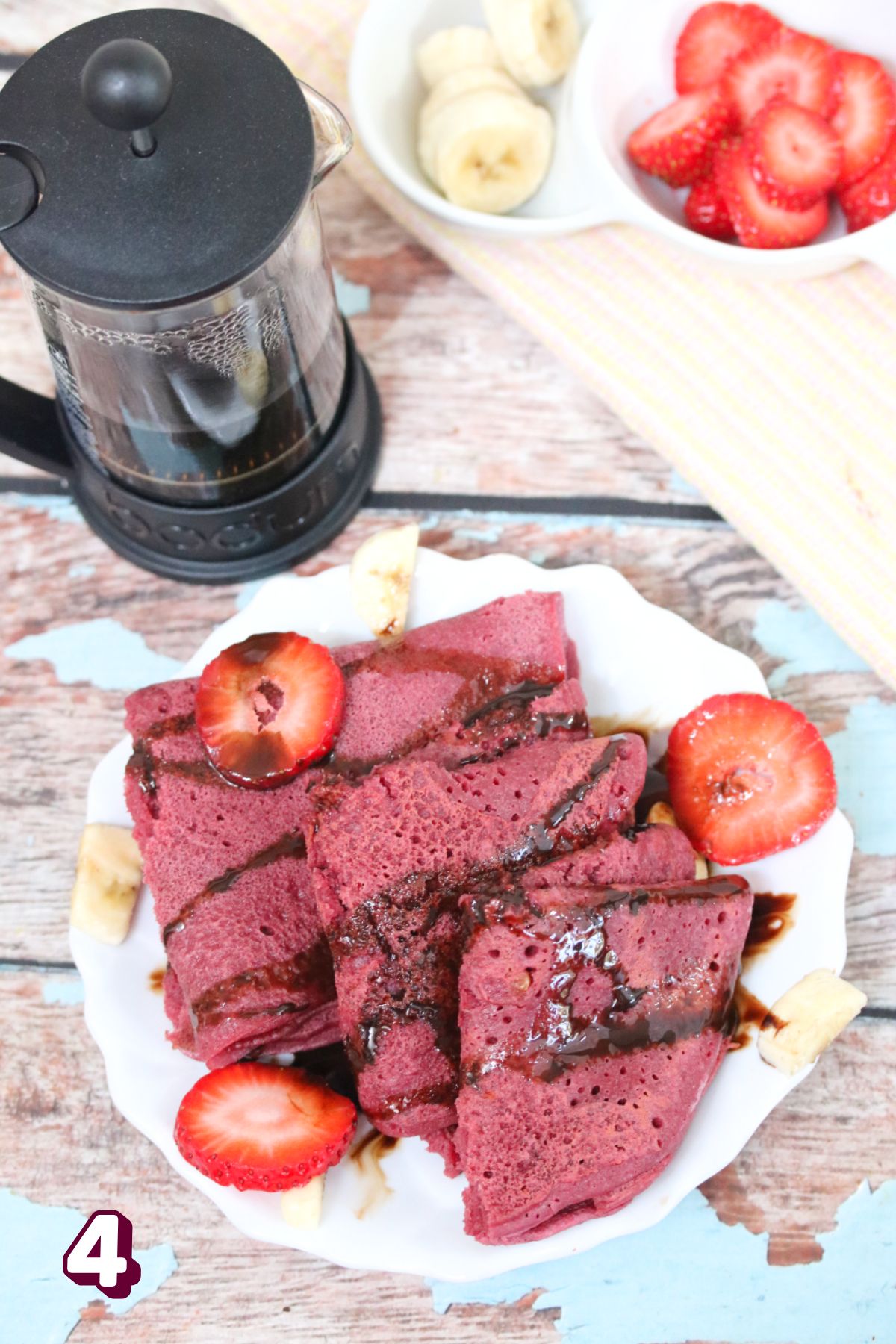 Three pink crepes folded on a white plate with berries.