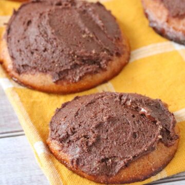 Cashew butter cookies frosted with chocolate on a yellow linen.
