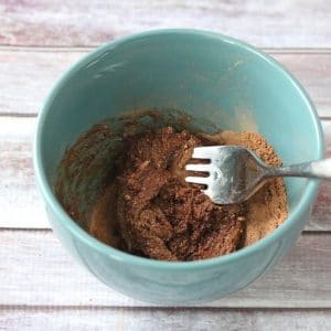 Blue bowl with paleo chocolate frosting ingredients being mixed