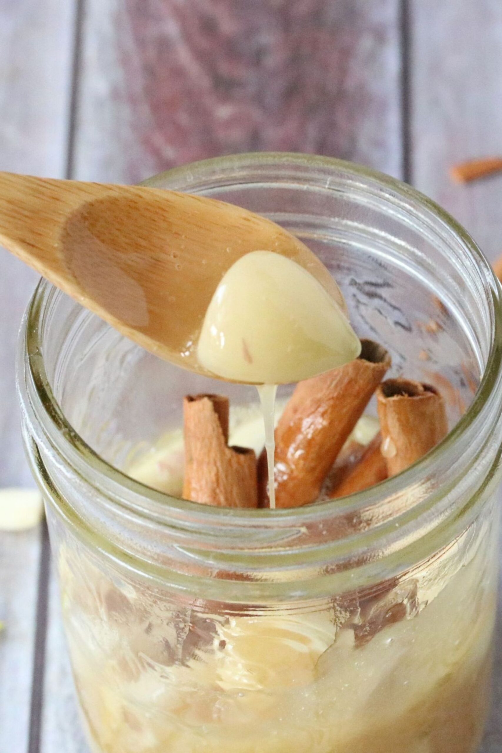 Fermented garlic and honey wit cinnamon in a jar and a spoon pulling out some.