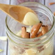 Mason jar with cinnamon, honey and garlic cloves and a wooden spoon pulling out a scoop