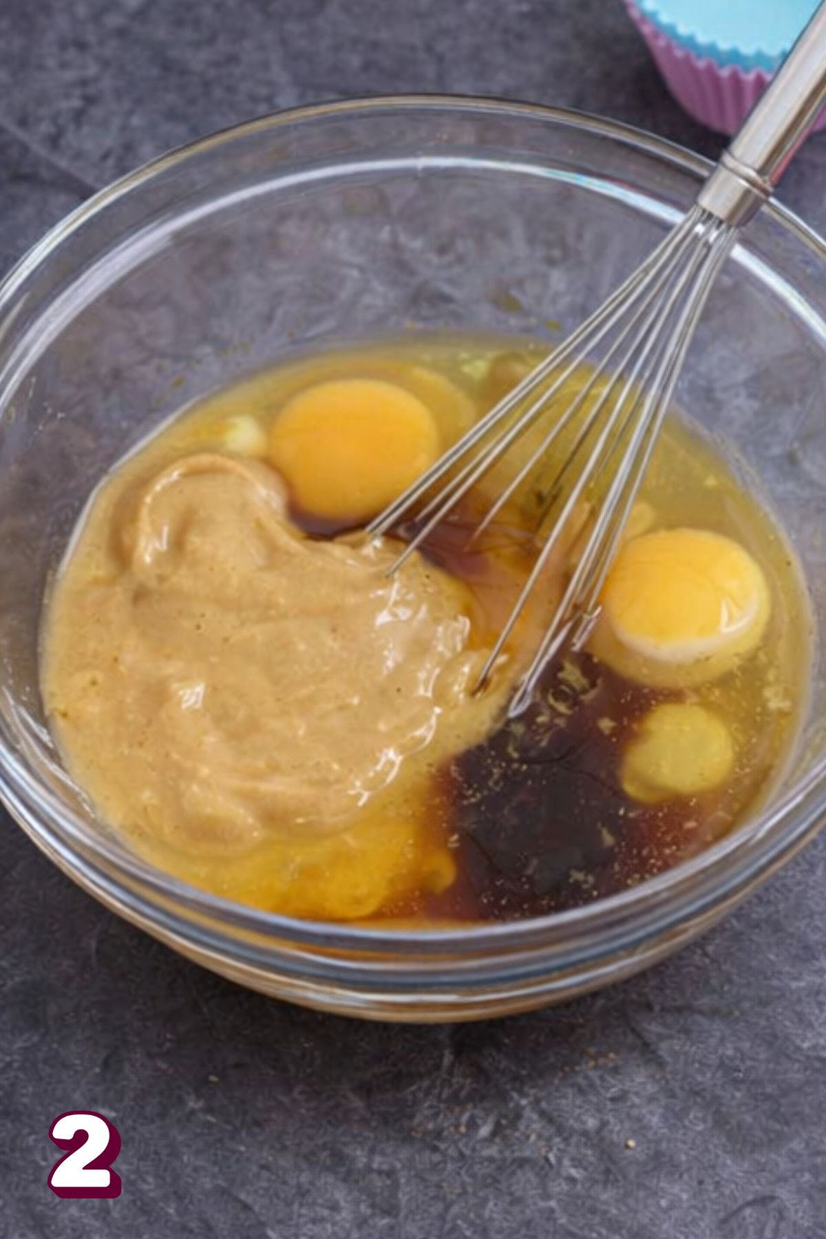 Eggs, cashew butter, and vanilla in a clear bowl with a whisk.