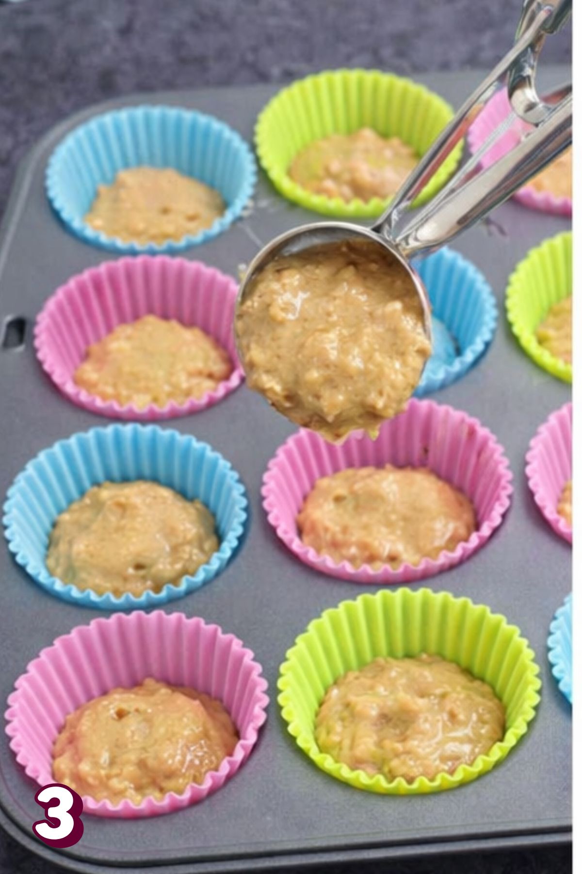 Pink, blue, and yellow cupcake liners in a baking pan with raw almond flour cupcake batter.