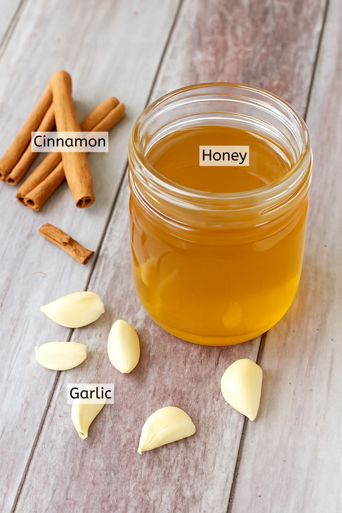 Honey in a large jar, cinnamon, and garlic with text labels over top.