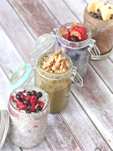 Four jars filled with different kinds of chia puddings recipes and topped with things like fresh berries, or nuts.