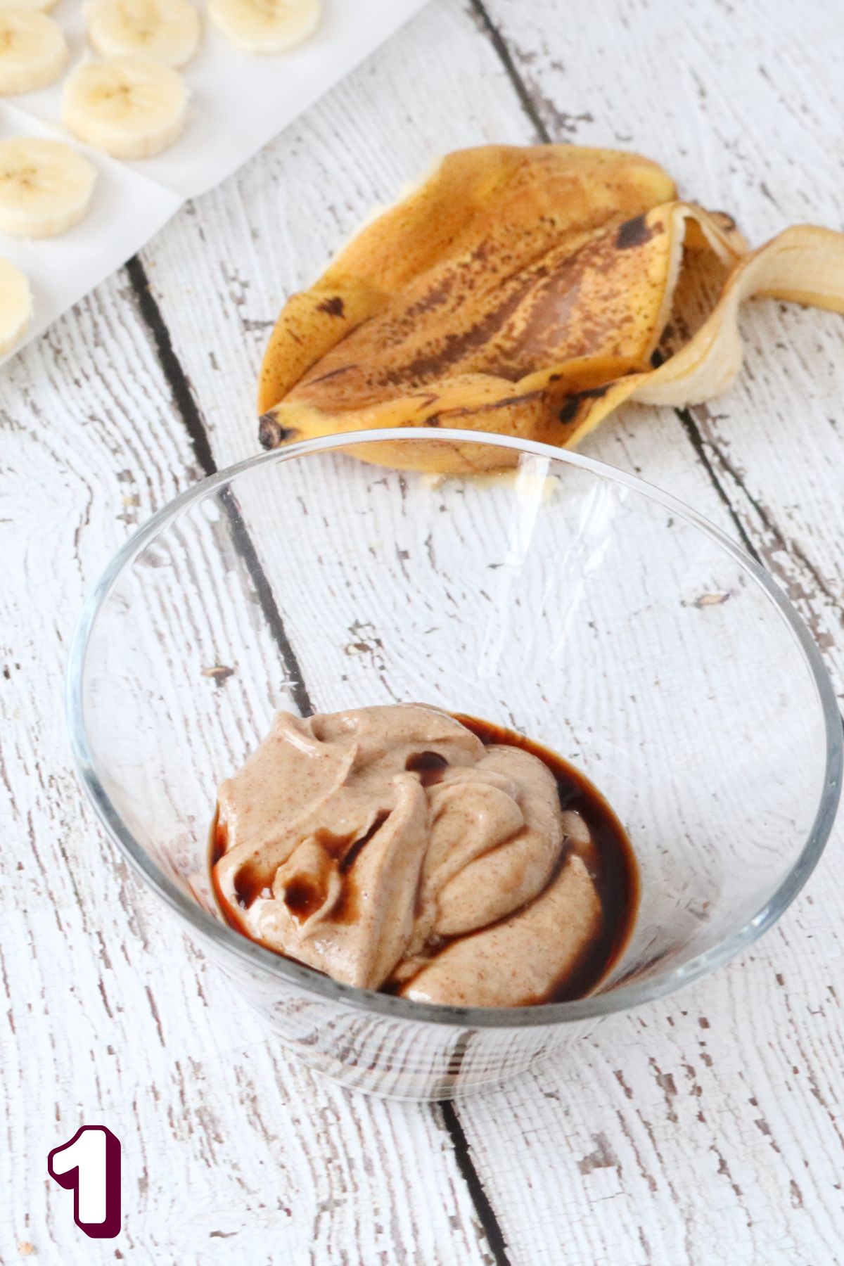 Frozen bananas: slices bananas on parchment paper with almond butter in a glass bowl.