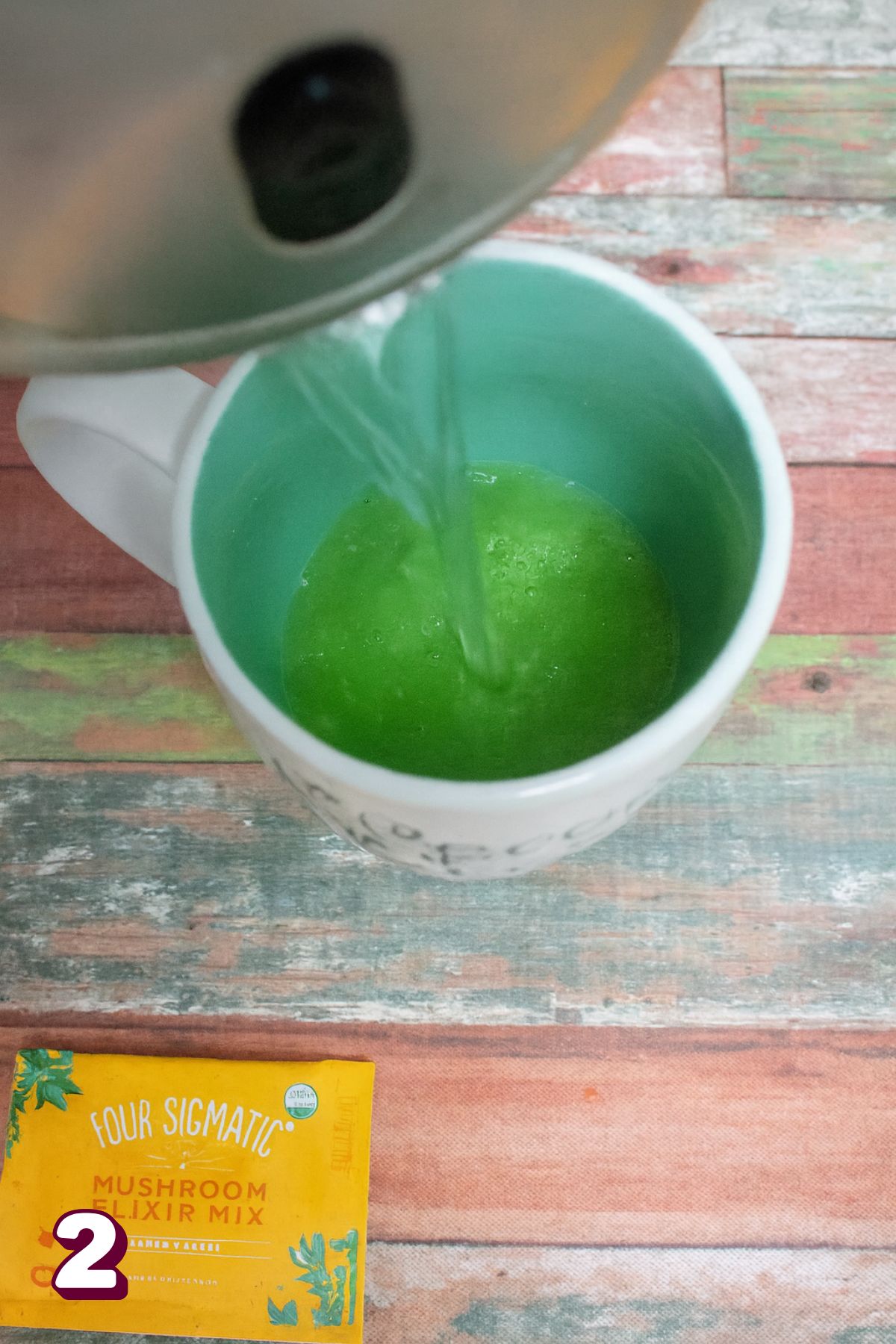 Boiling water being poured into a mug wth matcha powder.