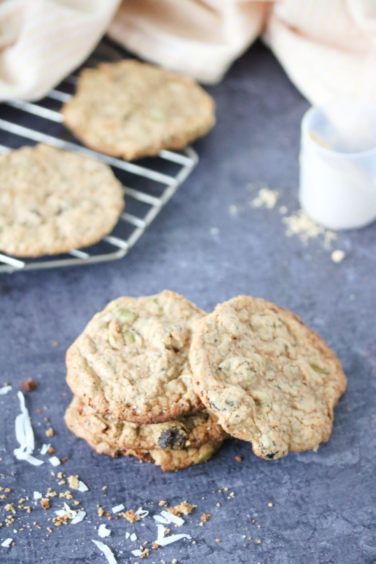 Vegan protein cookies stacked on one another with one off to the side and more behind them on a cooling rack.