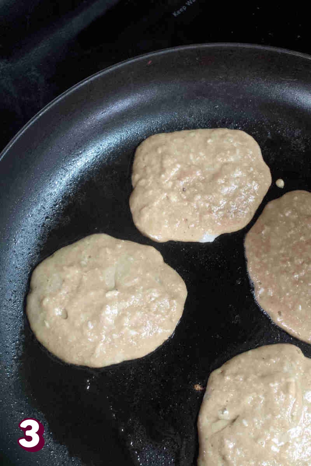 Almond flour protein pancakes being cooked in a pan.