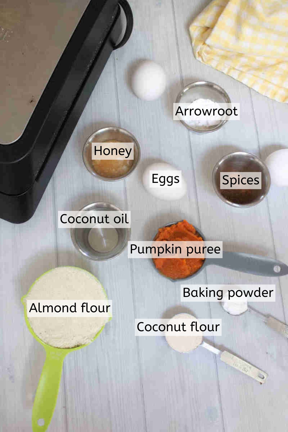 Multiple ingredients like pumpkin, eggs, flour, and honey in ramekins with text labels over top.