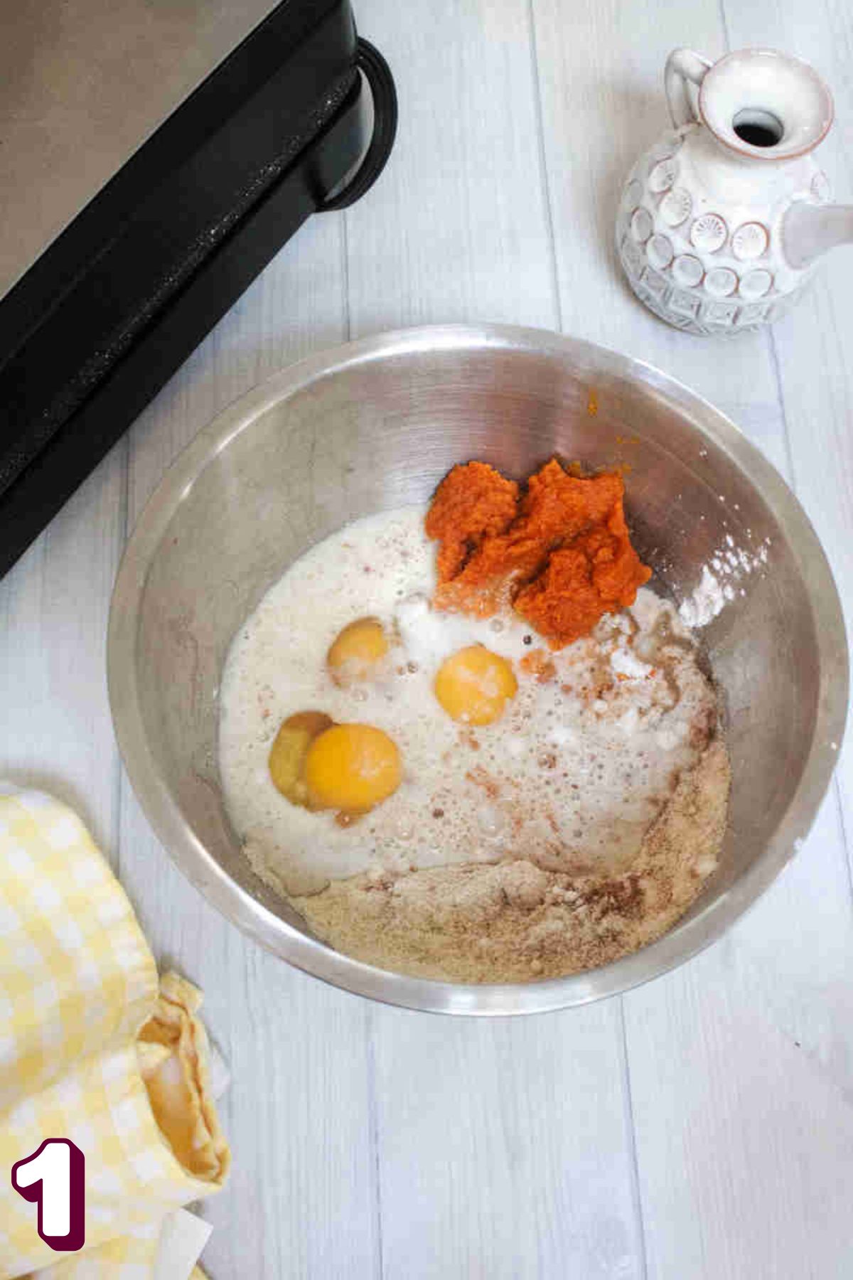 Raw eggs, pumpkin, milk, and almond flour in a steel bowl.