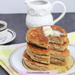 Featured image: four dairy-free pancakes stacked on a plate with syrup and butter with the plate on a colorful linen and coffee behind the plate