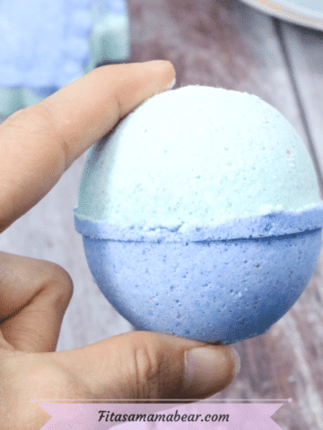 Featured image: blue and green bath bomb being held between two fingers with bath bombs behind it