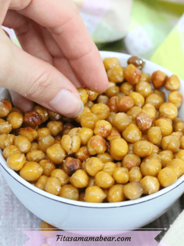 Featured image with text: salt and vinegar roasted chickpeas in a white bowl with a hand grabbing for them