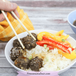 Pinterest image with text: pair of chopsticks grabbing a teriyaki meatball out of a bowl with rice and peppers, sauce and a yellow linen behind it.